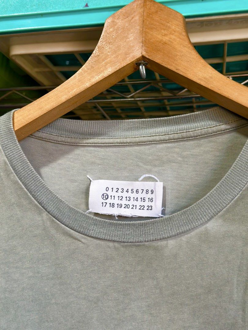 Maison Margiela Olive Acid Washed Tee Size 48 (Category: Shirts) located in Daet. Submitted by thrifthings2018 (Listing ID 1464840190, Image 3). Description: - Brand: Maison Margiela - Item: Olive Acid-Washed T-Shirt - Size: 48 (Made in Italy) - Details: Iconic numeric tag on the back collar - Condition: Pre-owned, with minor stains on the sleeve as pictured.