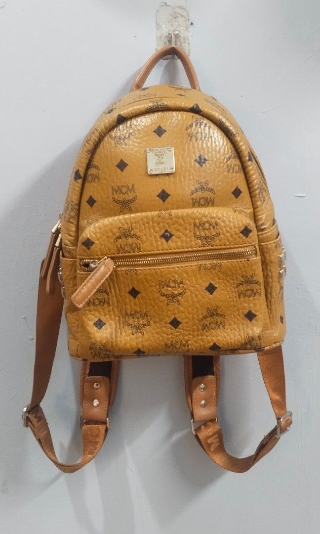 MCM stark vosetos back pack (Category: Luxury Bags & Wallets) located in Trece Martires City. Submitted by vherma (Listing ID 1464773744, Image 2). Description: This appears to be an MCM Stark Visetos Backpack in cognac. Brand & Style: MCM signature coated canvas monogram design in the classic cognac colorway. Features: Front zip pocket, top carry handle, and adjustable shoulder straps with gold-tone hardware. Pricing: Authentic versions typicall