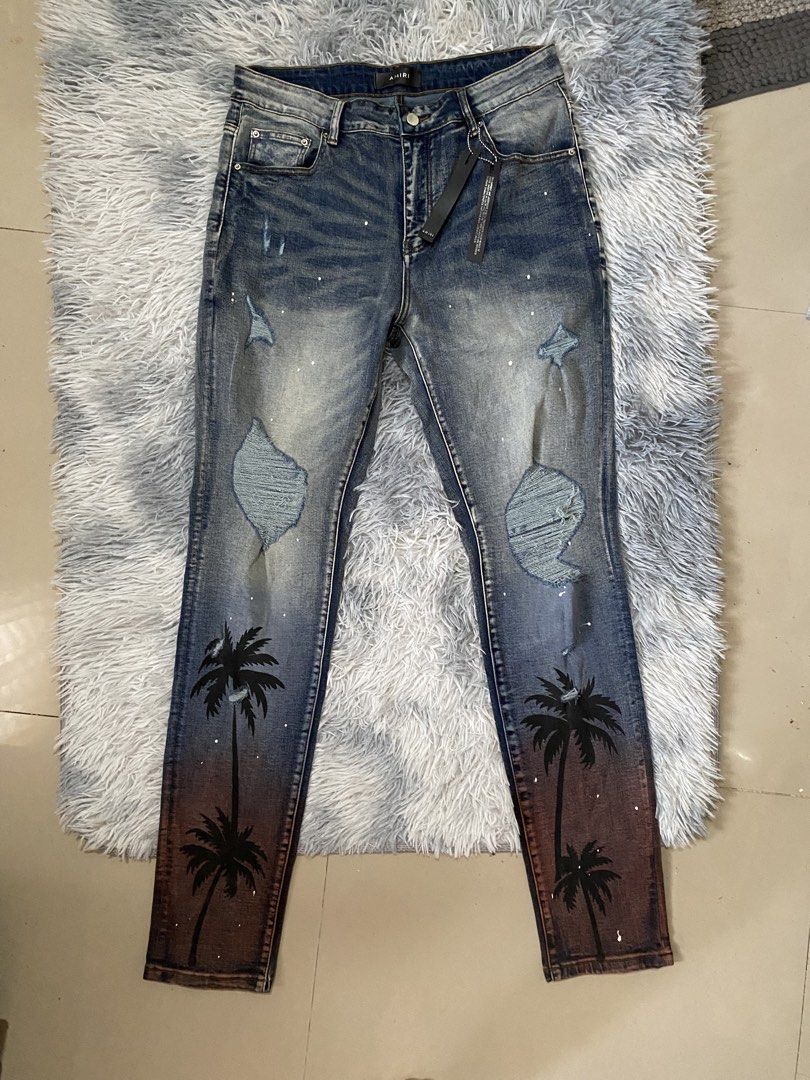 Men's Amiri Palm Trasher Jeans (Category: Jeans) located in Carmen. Submitted by yawbuangaka (Listing ID 1464824832, Image 2). Description: This is the distressed Amiri Palm Thrasher Jeans featuring a distinctive palm tree graphic and sunset-gradient wash near the cuffs. •Waistline - 34 •Length - 43 •Bnew with tags •Excellent.