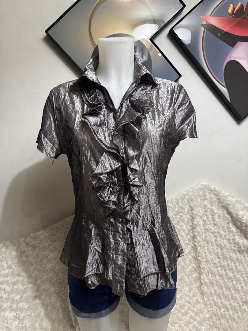 Metallic Silver Ruffle Short Sleeve Blouse (Category: Blouses) located in Marikina City. Submitted by lorradel (Listing ID 1464898312, Image 1). Description: - M on tag fits up to Large - Metallic silver short sleeve blouse with a unique crinkled texture - Features a button-up front with dramatic ruffles along the placket and collar - Flared hem provides a flattering and stylish shape - Lightweight material with a subtle, elegant sheen - Versatil