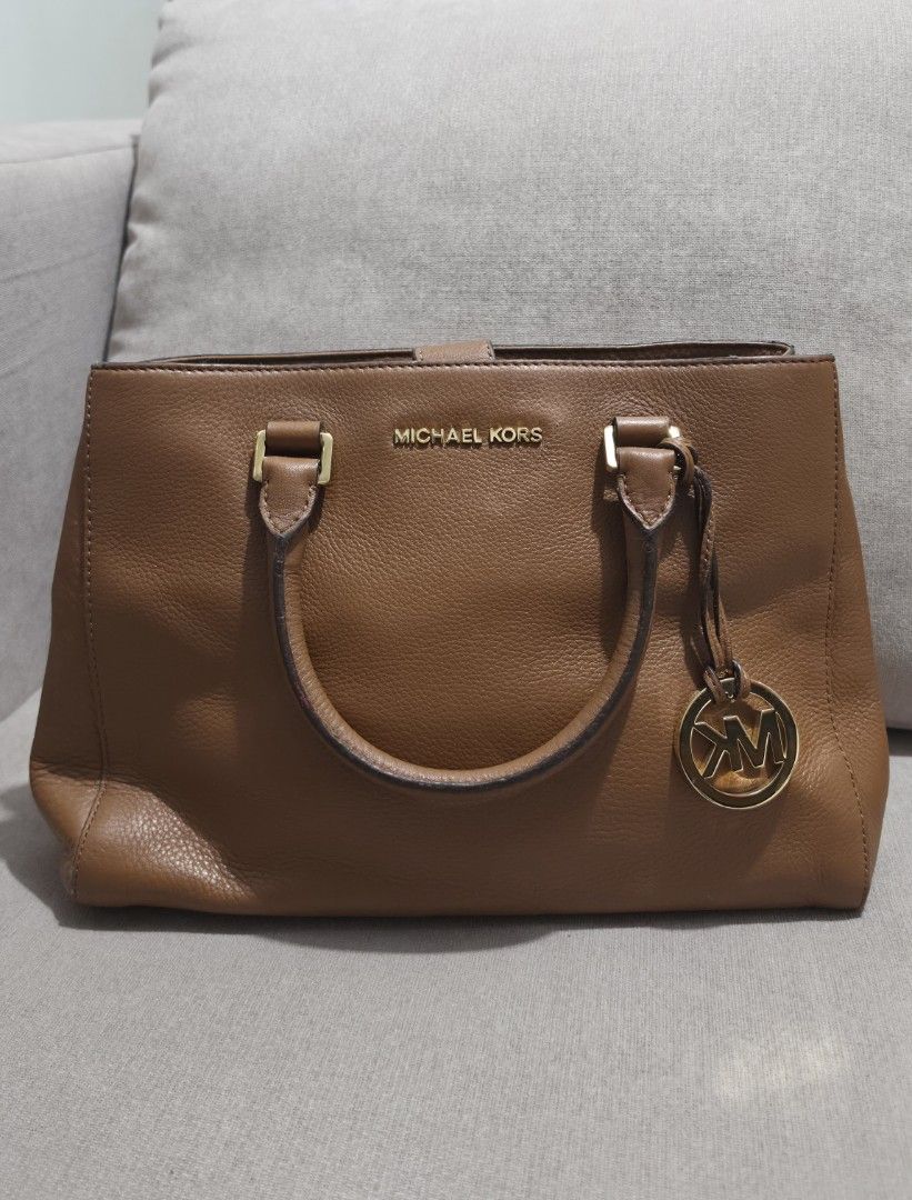 Michael Kors Brown Leather Tote Handbag with Strap (Category: Shoulder Bags) located in Makati City. Submitted by edgeeh (Listing ID 1464912996, Image 2). Description: - Brand: Michael Kors - Material: Rich brown pebbled leather with clean grain texture - Hardware: Premium gold-tone hardware with iconic MK circle logo charm - Carry Options: Dual top handles and a detachable, adjustable shoulder strap - Protection: Metal feet on the bottom panel t