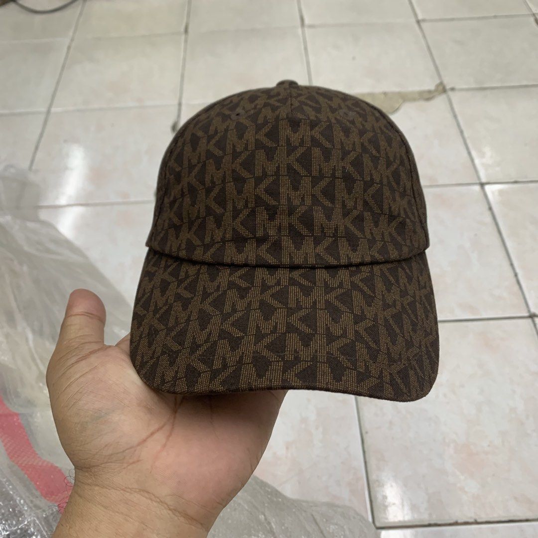 Michael Kors Brown MK Monogram Baseball Cap (Category: Caps & Hats) located in Cebu City. Submitted by jkeive (Listing ID 1464831601, Image 1). Description: - Brand: Michael Kors - Design: All-over signature monogram print in brown - Material: 100% cotton shell and lining for breathable comfort - Fit: Adjustable back strap with a branded gold-tone metal buckle - Details: Interior branded taping and sewn-in care label - Care Instructions: Hand was