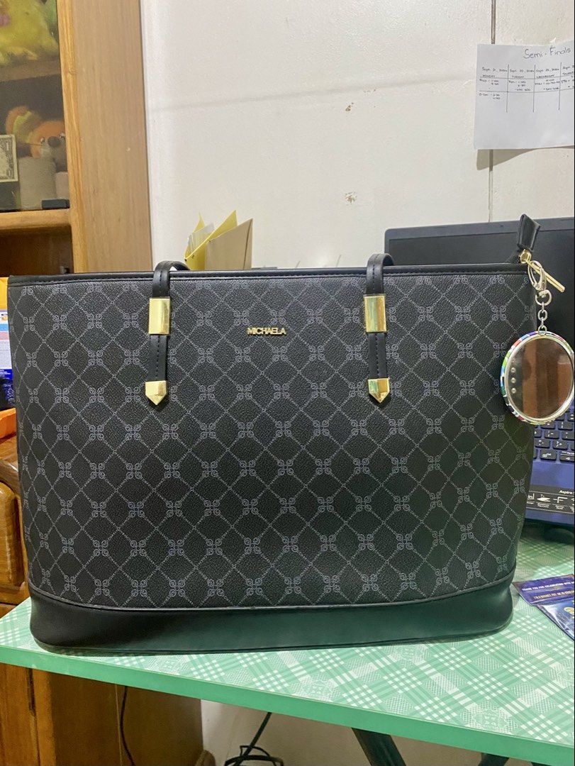 MICHAELA Black Monogram Tote Bag with Charm (Category: Tote Bags) located in Aloran. Submitted by free_marynette (Listing ID 1464900010, Image 1). Description: - Brand: MICHAELA - Color: Classic black with repeating monogram pattern - Hardware: Elegant gold accents - Design: Structured silhouette with dual shoulder straps and a stylish circular keychain charm - Interior: Spacious main compartment, perfect for daily essentials, work, or school - C