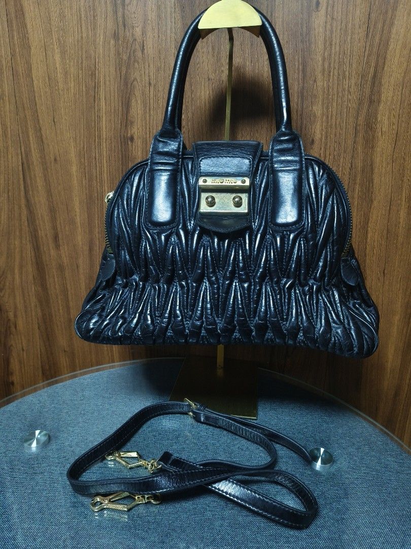 Miu Miu Matelassé Black Leather Bag (Category: Luxury Bags & Wallets) located in Baguio. Submitted by PreiLoveMaria (Listing ID 1464882121, Image 2). Description: Miu Miu Matelassé Black Leather Handbag (Japan Surplus Find!) ​Details: ​Style: Iconic Miu Miu matelassé pleated leather design featuring dual rolled top handles and gold-tone hardware. ​Closure & Accents: Front push-lock flap closure with the signature miu miu logo and dual top zippers