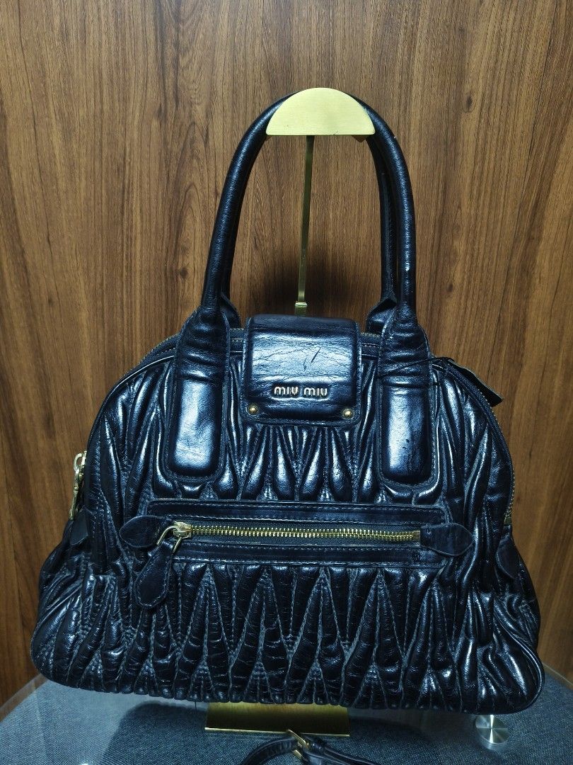 Miu Miu Matelassé Black Leather Bag (Category: Luxury Bags & Wallets) located in Baguio. Submitted by PreiLoveMaria (Listing ID 1464882121, Image 3). Description: Miu Miu Matelassé Black Leather Handbag (Japan Surplus Find!) ​Details: ​Style: Iconic Miu Miu matelassé pleated leather design featuring dual rolled top handles and gold-tone hardware. ​Closure & Accents: Front push-lock flap closure with the signature miu miu logo and dual top zippers