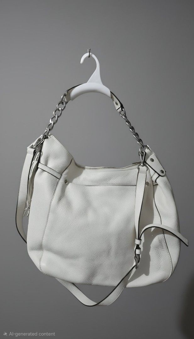 MK White Leather Shoulder Bag with Chain Strap (Category: Shoulder Bags) located in Makati City. Submitted by edgeeh (Listing ID 1464912171, Image 1). Description: White leather hobo bag by Coach. Silver-tone chain detail on the top handle, plus a longer adjustable strap. Zipper closure across the top. Fringe tassel hanging off the side. Clean pebble grain texture all over. Roomy interior for daily essentials..