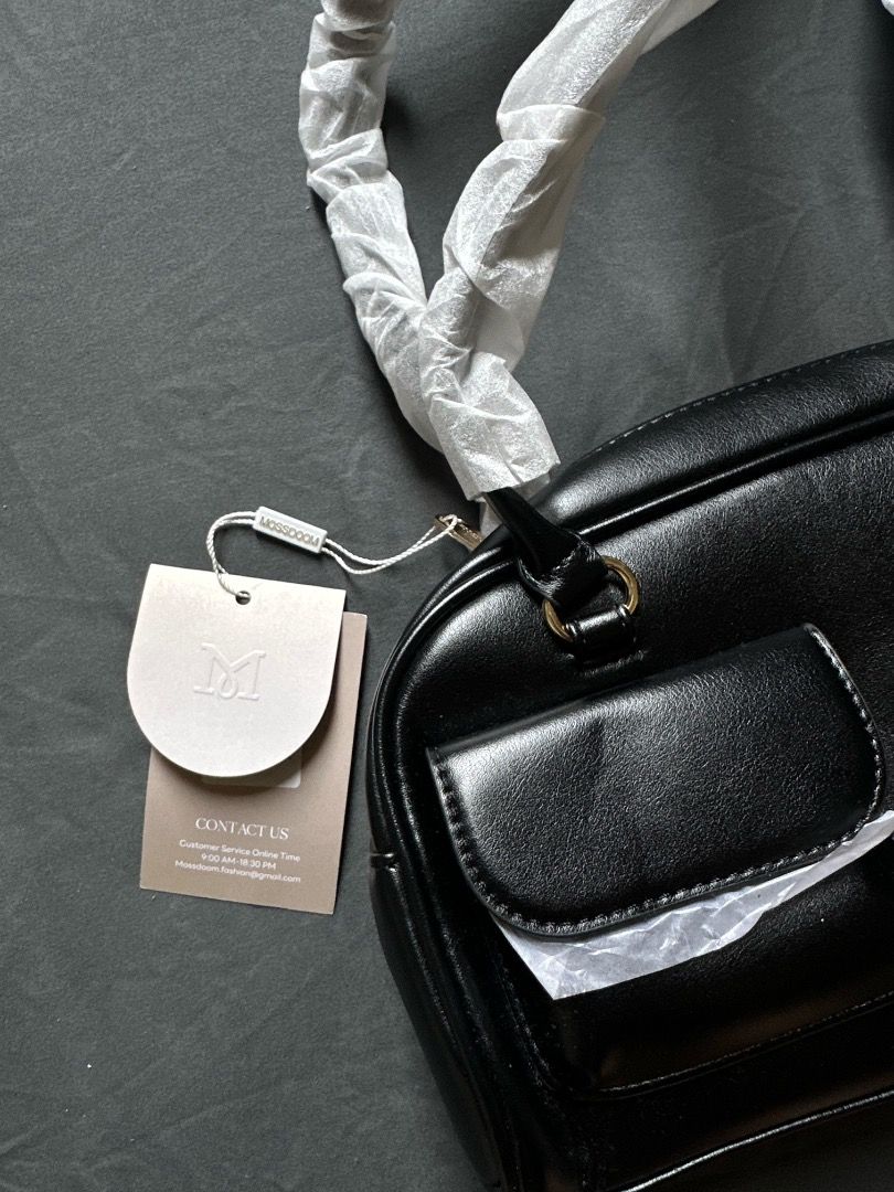 MOSSDOOM Black Shoulder Bag (Category: Shoulder Bags) located in Manila. Submitted by shopwmsl123 (Listing ID 1464785941, Image 2). Description: - Brand: MOSSDOOM - Color: Clean black with chic gold-tone hardware - Style: Shoulder bag - Pockets: Front zip closure pocket and small flap pocket - Condition: Brand new with tag attached - Extra: Handles still wrapped in original protective paper.
