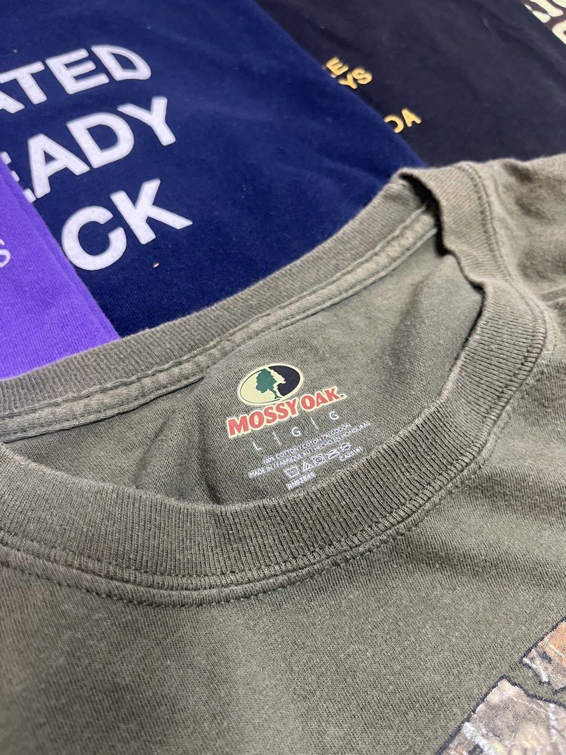 Mossy Oak Green Graphic Tee Size L (Category: Tshirts & Polo Shirts ) located in Baao. Submitted by plainclothesdept (Listing ID 1464785385, Image 3). Description: Mossy Oak width - 22 in. length- 28 in. no flaws - Brand: Mossy Oak - Color: Olive Green - Design: Large chest logo with camo fill and oval border - Material: 100% Cotton (Made in Honduras) - Fit: Standard crew neck, short sleeves - Condition: Clean fabric with minimal fading around th
