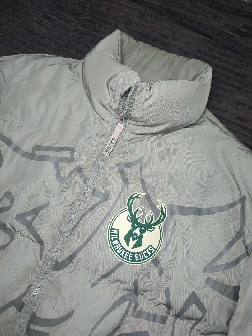 NBA Milwaukee Bucks Puffer Jacket Grey (Category: Coats, Jackets and Outerwear) located in Manila. Submitted by norathrifted (Listing ID 1464801338, Image 3). Description: - Authentic Milwaukee Bucks winter puffer jacket in grey - Full zip front closure with a warm stand collar - Features Milwaukee Bucks team logo on chest and large lettering across the back - NBA logo patch detailed on the left sleeve - Trendy subtle graffiti print pattern throu