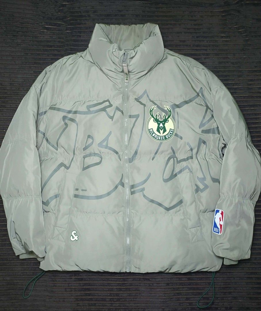 NBA Milwaukee Bucks Puffer Jacket Grey (Category: Coats, Jackets and Outerwear) located in Manila. Submitted by norathrifted (Listing ID 1464801338, Image 1). Description: - Authentic Milwaukee Bucks winter puffer jacket in grey - Full zip front closure with a warm stand collar - Features Milwaukee Bucks team logo on chest and large lettering across the back - NBA logo patch detailed on the left sleeve - Trendy subtle graffiti print pattern throu