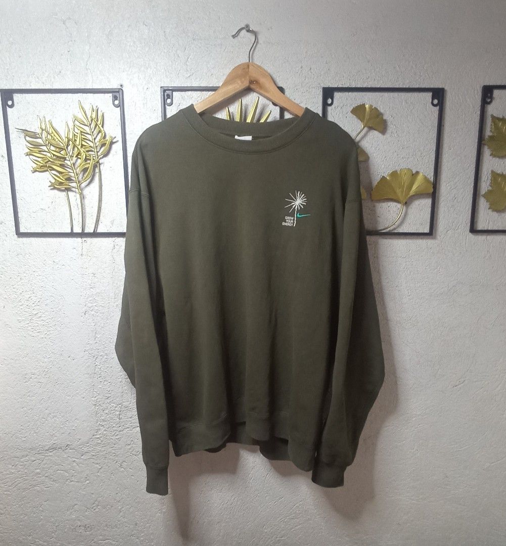 Nike Crewneck Army Green (Category: Coats, Jackets and Outerwear) located in Kawit. Submitted by deidzdzn (Listing ID 1464796395, Image 3). Description: - Brand: Nike - Style: Grow Your Energy Crewneck Sweatshirt - Color: Army Green - Design: Embroidered dandelion and Nike logo graphic on the chest - Fit: Relaxed fit with ribbed collar, cuffs, and hem - Size: XL - Measurements: Width 25 inches, Length 27 inches.
