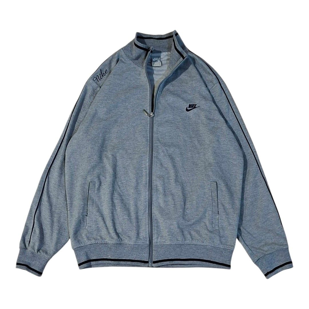 Nike Gray Track Jacket Full Zip XL (Category: Coats, Jackets and Outerwear) located in Manila. Submitted by joshbelgic17602 (Listing ID 1464935633, Image 1). Description: - Brand: Nike - Style: Full-zip track jacket - Color: Gray with black piping details - Size: XL - Logos: Small embroidered Nike logo on left chest, cursive Nike print on right shoulder - Pockets: Two side welt pockets - Details: Ribbed cuffs and hem - Condition: Clean fabric and
