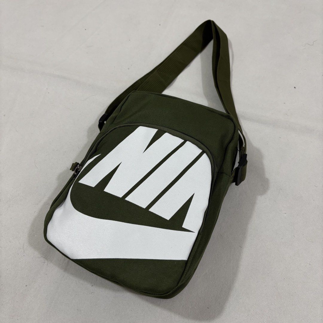 Nike Green Crossbody Bag (Category: Sling Bags) located in Cavite. Submitted by itsayaaa (Listing ID 1464836895, Image 2). Description: - Color: Olive green with big white Nike logo on front - Material: 100% polyester (Made in Vietnam) - Features: Adjustable shoulder strap and secure main zipper compartment - Condition: Clean inside and out - Usage: Handy daily carry, fits phone, keys, and wallet easily.