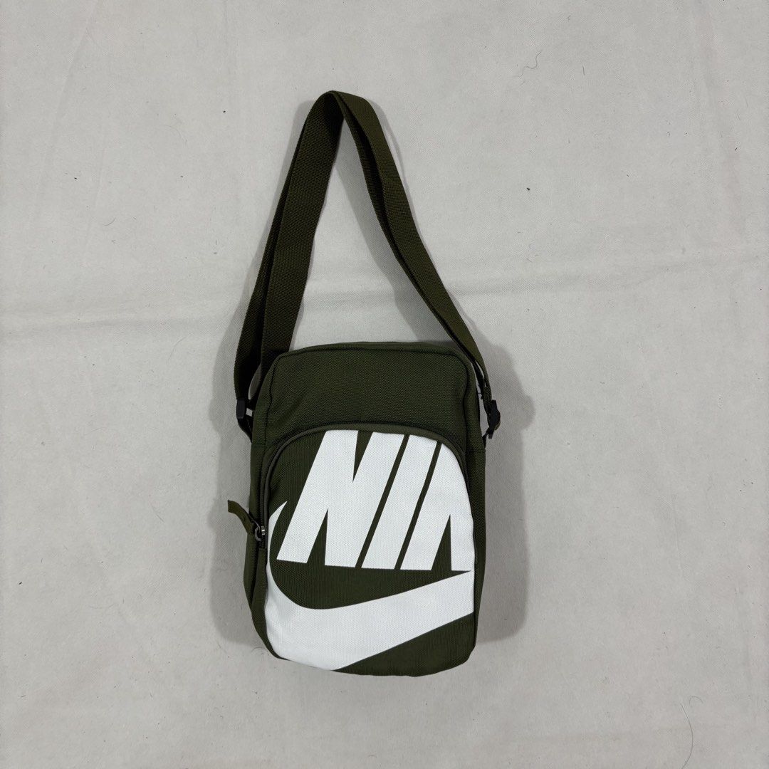 Nike Green Crossbody Bag (Category: Sling Bags) located in Cavite. Submitted by itsayaaa (Listing ID 1464836895, Image 1). Description: - Color: Olive green with big white Nike logo on front - Material: 100% polyester (Made in Vietnam) - Features: Adjustable shoulder strap and secure main zipper compartment - Condition: Clean inside and out - Usage: Handy daily carry, fits phone, keys, and wallet easily.