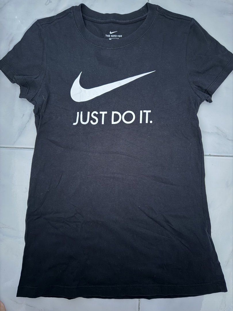 Nike Just Do It Black Tee Size M (Category: Shirts) located in Paranaque City. Submitted by yukigrace12 (Listing ID 1464799179, Image 1). Description: - Brand: Nike - Color: Black - Size: Medium (The Nike Tee) - Design: Large white Swoosh graphic with 'JUST DO IT.' text on the chest - Details: Round collar, made in Turkey - Product Code: CI1384-010 - Condition: Clean fabric with standard wear.