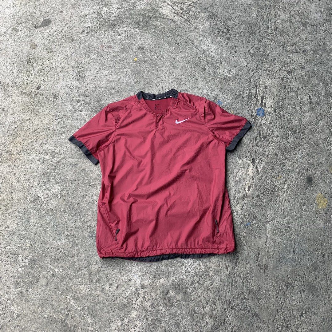Nike Short Sleeve V-Neck Windbreaker Maroon (Category: Activewear) located in Polangui. Submitted by b0ssl00ts (Listing ID 1464805504, Image 1). Description: - Brand: Nike - Style: Short-sleeve windbreaker - Color: Maroon with dark grey shoulder and cuff panels - Size: Medium - Details: V-neck collar with repeated Nike branding inside, small white Swoosh on left chest - Pockets: Two zippered pockets near the hem with grey pull cords - Origin: Mad