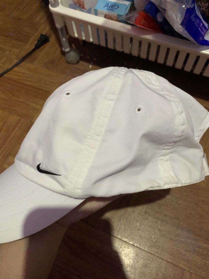 Nike White Baseball Cap (Category: Caps & Hats) located in Manila. Submitted by usagichan_rabbit (Listing ID 1464797702, Image 2). Description: - Brand: Nike - Color: White with black embroidered swoosh logo - Material: 60% cotton, 40% polyester blend - Size: One size fits all with adjustable back strap - Details: Features a small black swoosh on the strap and grey trim underneath the brim - Condition: Inner band shows some discoloration from wea