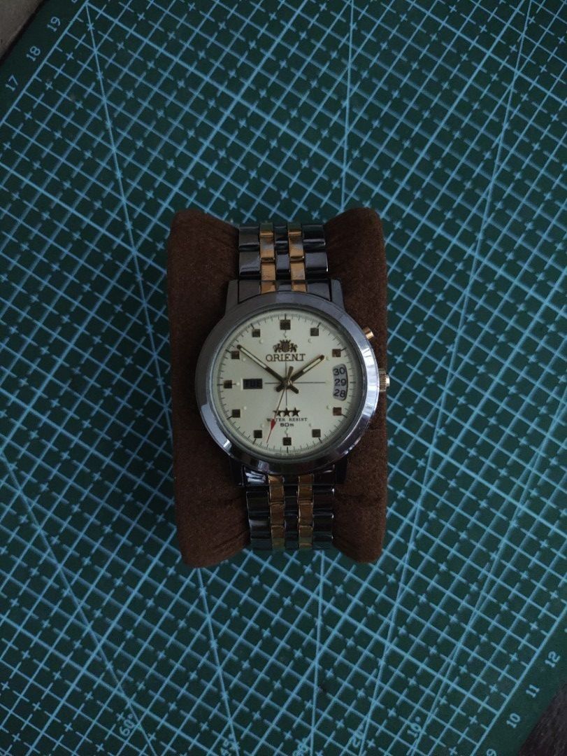 Orient Tri Star Two Tone Automatic Watch (Category: Men's Watches) located in Mangatarem. Submitted by kacchon (Listing ID 1464801272, Image 1). Description: - Brand: Orient Tri Star - Dial: Classic cream dial with day display at 9 o'clock and date display near 3 o'clock - Rare Two-tone black and gold finish on case and bracelet - Water Resistance: Up to 50 meters - 38mm case and can fit wrist size 7+ - Condition: Minor hairline scratches on the 