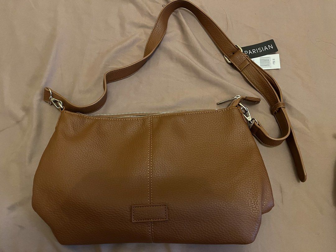 Parisian Brown Shoulder Bag (Category: Shoulder Bags) located in Cavite. Submitted by ekasbeautyandtoysroom (Listing ID 1464850551, Image 1). Description: - Brand: Parisian (Tag still attached) - Color & Material: Brown faux leather with a pebbled finish - Strap: Long, adjustable strap with secure metal clasps - Closure: Double zip top closure - Design: Center vertical stitch detail with a chic front patch.