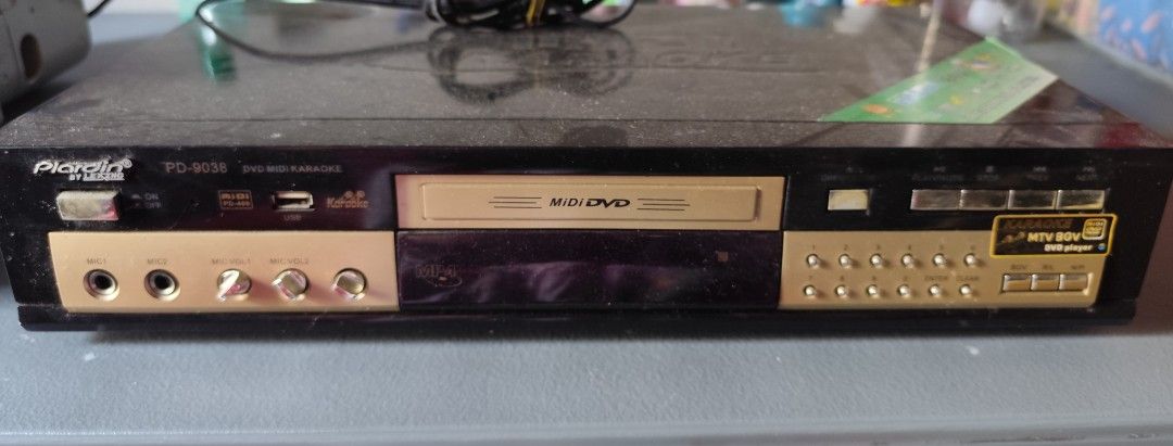 Plardin PD-9038 Midi DVD Karaoke Player (Category: Blu-Ray & Media Players) located in Valenzuela. Submitted by xjepsx (Listing ID 1464815766, Image 1). Description: - Brand/Model: Plardin PD-9038 Digital Karaoke DVD Player - Design: Stylish black chassis with elegant gold accents - Key Features: Dual microphone inputs, front USB port, manual volume knobs, and front number pad buttons - Condition: Good working condition, just needs a quick wipe d