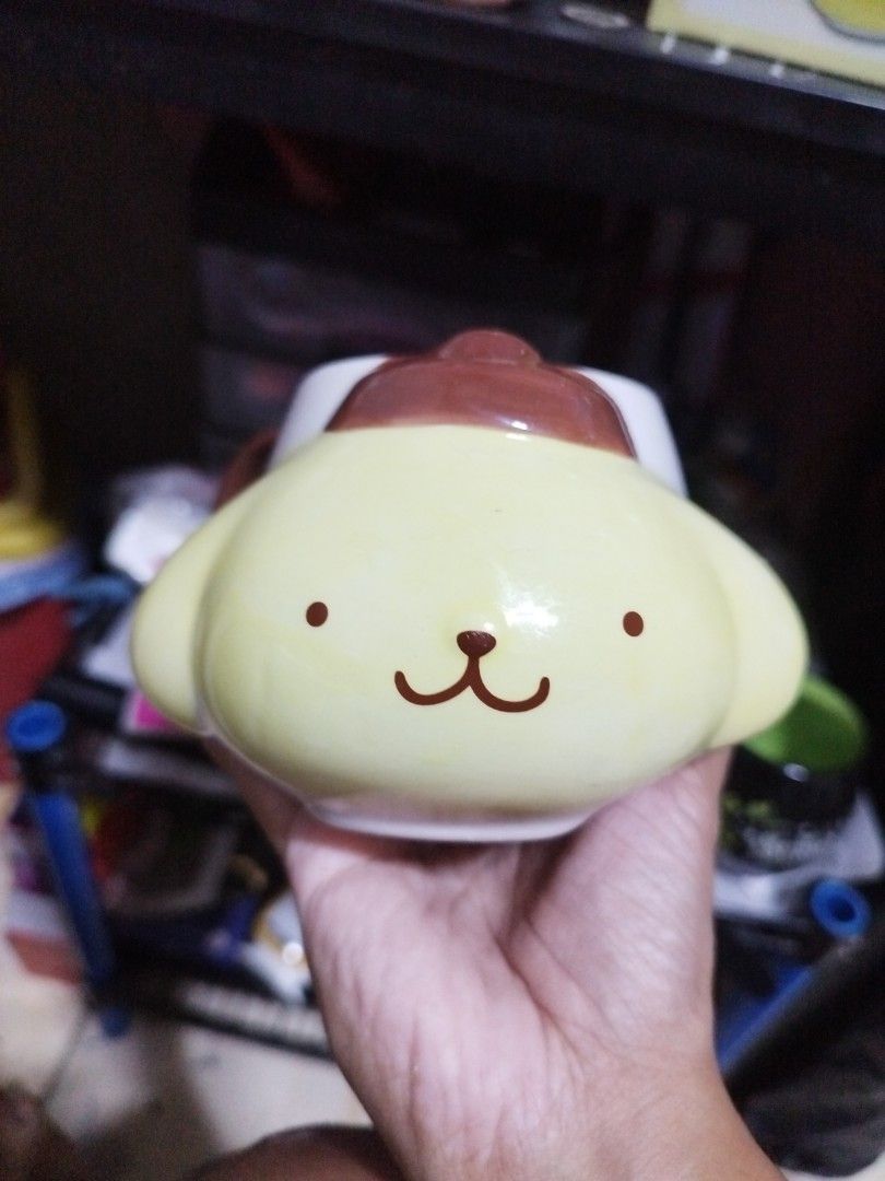 Pompompurin Character Ceramic Coffee Mug (Category: Coffee & Tea Tableware) located in Manila. Submitted by silverwhale_cafa21 (Listing ID 1464794666, Image 2). Description: - Official Pompompurin face design in bright yellow - Unique brown beret shaped as part of the rim - Standard size, perfect for morning coffee or tea - Cute printed facial details - Flaw: Small paint chip near the bottom curve of the brown handle.