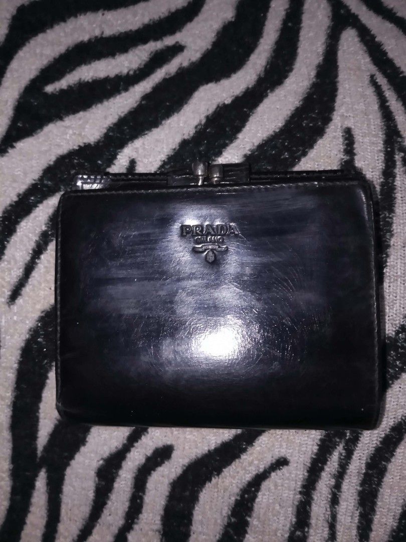 Prada Black Leather Wallet with Kiss Lock (Category: Luxury Bags & Wallets) located in Valenzuela. Submitted by rowenasalvador777 (Listing ID 1464968688, Image 1). Description: - Brand: Prada - Material: Polished leather in classic black - Closure: Secure top clasp - Branding: Iconic embossed Prada Milano logo on the front - Design: Compact and pocket-friendly for daily use - Perfect for: Carrying cards and cash essentials.