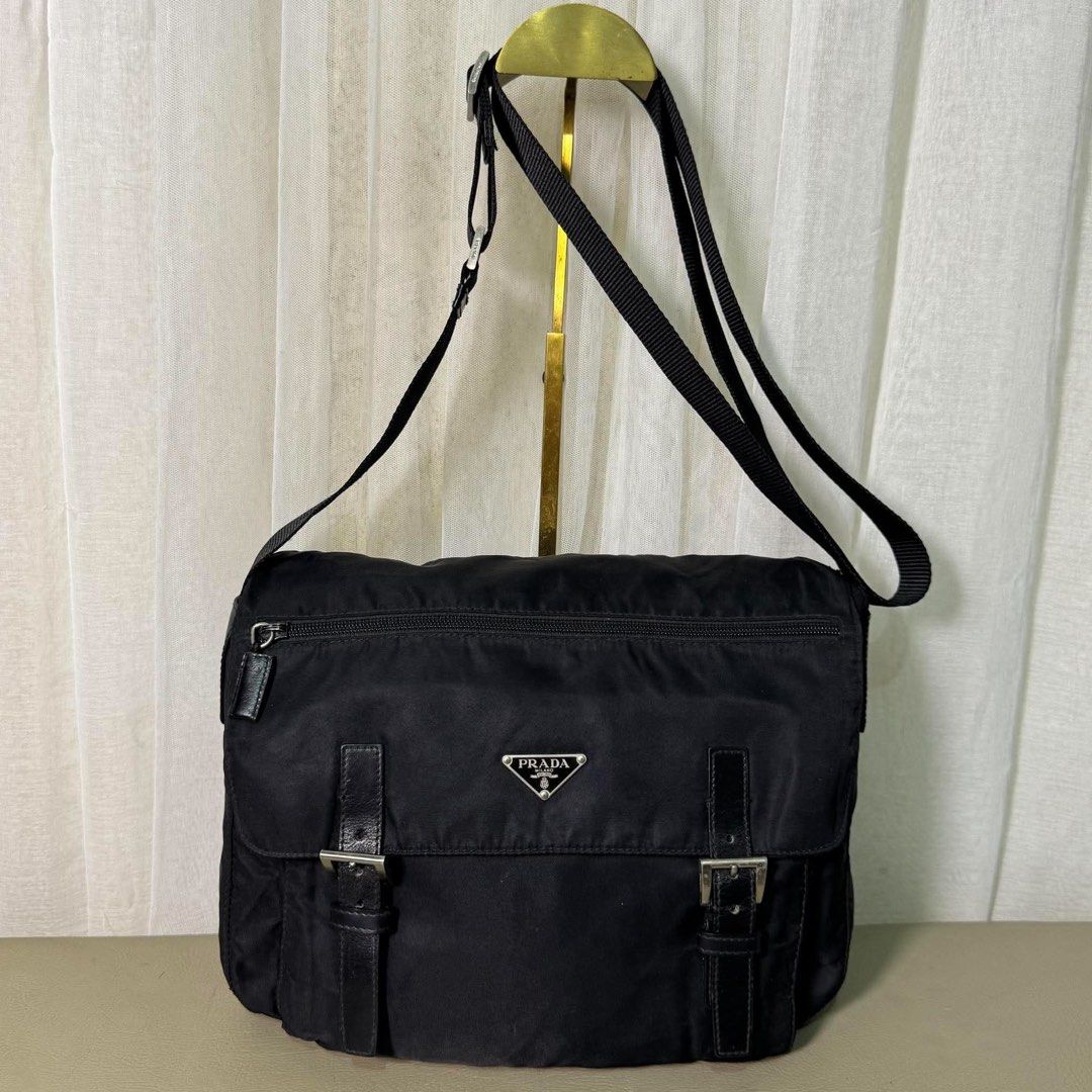 Prada Black Nylon Messenger Bag with Leather Straps (Category: Luxury Bags & Wallets) located in Madrid. Submitted by jhunaceee (Listing ID 1464892670, Image 1). Description: - Authentic Prada messenger bag in classic black durable nylon - Iconic triangular Prada logo plaque on the front - Front flap closure with stylish dual leather straps and metal buckles - Handy exterior zippered pocket for quick-access items - Adjustable fabric shoulder stra