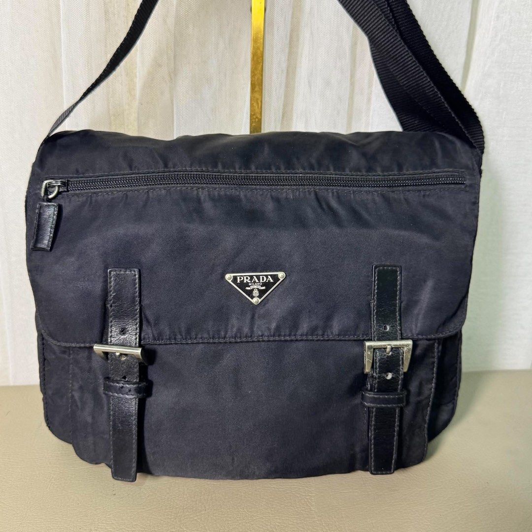 Prada Black Nylon Messenger Bag with Leather Straps (Category: Luxury Bags & Wallets) located in Madrid. Submitted by jhunaceee (Listing ID 1464892670, Image 3). Description: - Authentic Prada messenger bag in classic black durable nylon - Iconic triangular Prada logo plaque on the front - Front flap closure with stylish dual leather straps and metal buckles - Handy exterior zippered pocket for quick-access items - Adjustable fabric shoulder stra