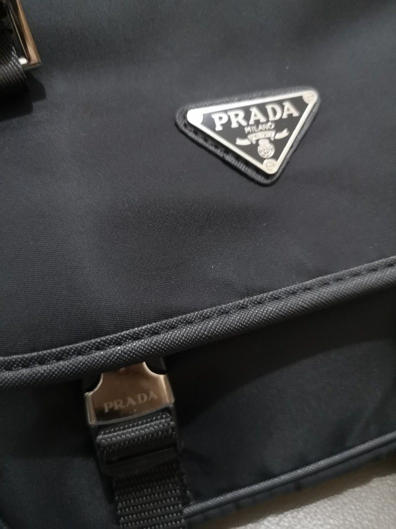Prada Black Nylon Messenger Bag with Strap (Category: Luxury Bags & Wallets) located in Manila. Submitted by lorenzomar99185 (Listing ID 1464905470, Image 2). Description: - Prada black nylon messenger bag - Iconic metal triangular logo on the front flap - Secure dual buckle closures - Adjustable fabric strap with woven branding and branded hardware - Compact daily size with convenient zipped compartments.