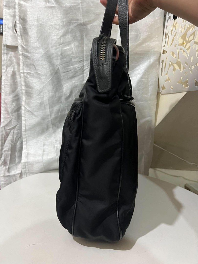 Prada Black Nylon Tote Bag (Category: Luxury Bags & Wallets) located in Quezon City. Submitted by luxuriesbymichiika (Listing ID 1464900645, Image 2). Description: - Authentic Black Prada tote bag in durable nylon - Dual textured leather top handles for comfortable wear - Front features two handy zippered utility pockets - Classic silver-tone enamel triangle logo detail - Secure top zip closure with spacious interior - Structured rectangular base