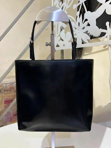 Prada Black Patent Leather Tote Handbag (Category: Purses & Pouches) located in Quezon City. Submitted by luxuriesbymichiika (Listing ID 1464942953, Image 2). Description: - Authentic Prada black patent leather tote bag - Glossy finish with sleek silver-tone hardware - Double thin shoulder straps with adjustable buckles - Structured square silhouette with clean stitching - Minimalist white Prada logo stamped near the top corner - Spacious interio