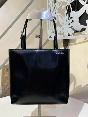 Prada Black Patent Leather Tote Handbag (Category: Purses & Pouches) located in Quezon City. Submitted by luxuriesbymichiika (Listing ID 1464942953, Image 1). Description: - Authentic Prada black patent leather tote bag - Glossy finish with sleek silver-tone hardware - Double thin shoulder straps with adjustable buckles - Structured square silhouette with clean stitching - Minimalist white Prada logo stamped near the top corner - Spacious interio
