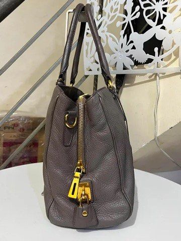 Prada Grey Leather Tote Handbag with Lock and Keys (Category: Tote Bags) located in Quezon City. Submitted by luxuriesbymichiika (Listing ID 1464943926, Image 3). Description: - 100% Authentic Prada pebbled leather tote in a chic dark greyish taupe shade - Spacious interior with secure zip compartments for your daily essentials - Elegant gold-tone hardware and iconic front metal logo lettering - Structured yet soft shape with protective metal fee