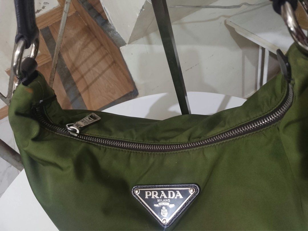 Prada Olive Green Nylon Hobo Shoulder Bag (Category: Luxury Bags & Wallets) located in Quezon City. Submitted by luxuriesbymichiika (Listing ID 1464898009, Image 2). Description: - Brand: Prada - Material: Durable nylon in olive green with dark brown Saffiano leather strap and side panels - Hardware: Silver-tone with secure zipper closure - Details: Iconic triangular metal Prada logo plaque on the front - Shape: Classic, slouchy hobo silhouette -