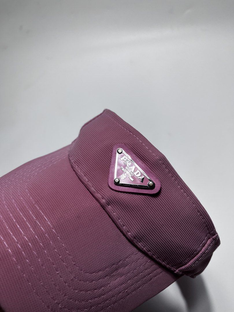 Prada Pink Visor Cap (Category: Hats & Beanies) located in Iloilo. Submitted by fromthebins.ilo2 (Listing ID 1464882967, Image 2). Description: - Brand: Prada - Item: Visor Cap - Color: Dusty pink with light blue interior branding - Hardware: Classic metal triangle logo plaque on the front - Fit: Adjustable back strap for a custom fit - Condition: Noticeable sweat staining and wear along the inner headband lining from previous use (sold as is) - 