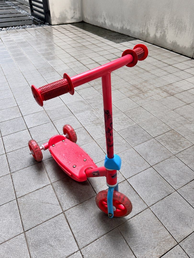 Red three-wheel kids kick scooter (Category: Skates, Rollerblades & Scooters) located in Muntinlupa City. Submitted by shopnb (Listing ID 1464782291, Image 1). Description: Cute and sturdy 3-wheel scooter for young kids — stable and easy to use for beginners. Features: * 3-wheel design for better stability * 2 rear wheels + 1 front wheel * Wide textured deck * Easy-grip handlebars * Rear foot brake * Adjustable-height handlebar * Lightweight and 