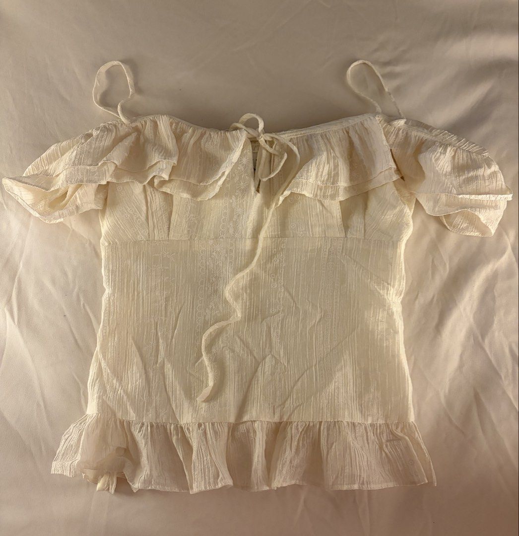 Rubies Saigon Ecru Cream Flowy Ruffled Smocked Top (Category: Sleeveless) located in Makati City. Submitted by chiclane_ (Listing ID 1464874064, Image 1). Description: pretty fabric! can be worn with the straps as cold shoulder top or off shoulder bought from rubies vietnam brand for reach only.