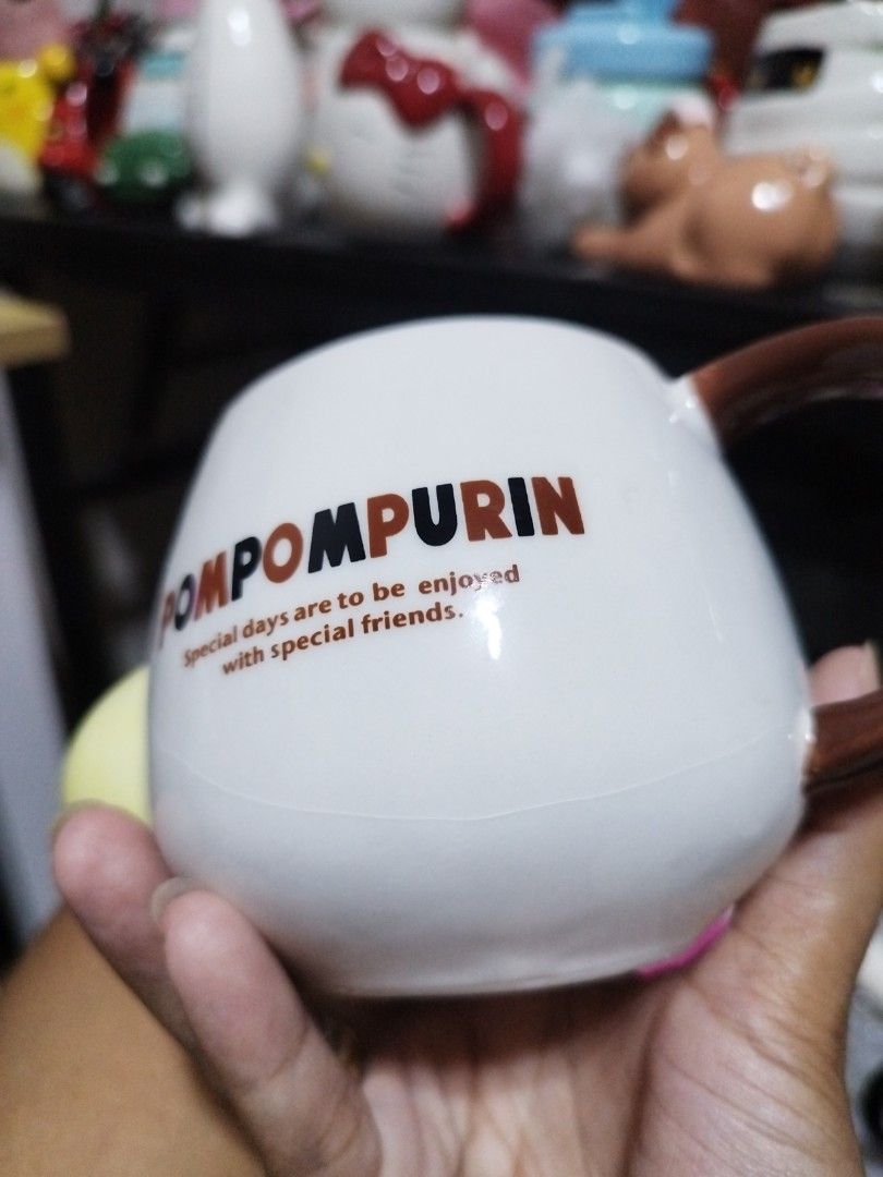 Sanrio Pompompurin ceramic mug with brown handle (Category: Coffee & Tea Tableware) located in Manila. Submitted by silverwhale_cafa21 (Listing ID 1464795025, Image 3). Description: - Authentic Pompompurin ceramic mug - Front design features Pompompurin's iconic yellow face with brown nose and mouth - Back features 'POMPOMPURIN' text and quote: 'Special days are to be enjoyed with special friends' - Accented with a cute brown handle on the side -