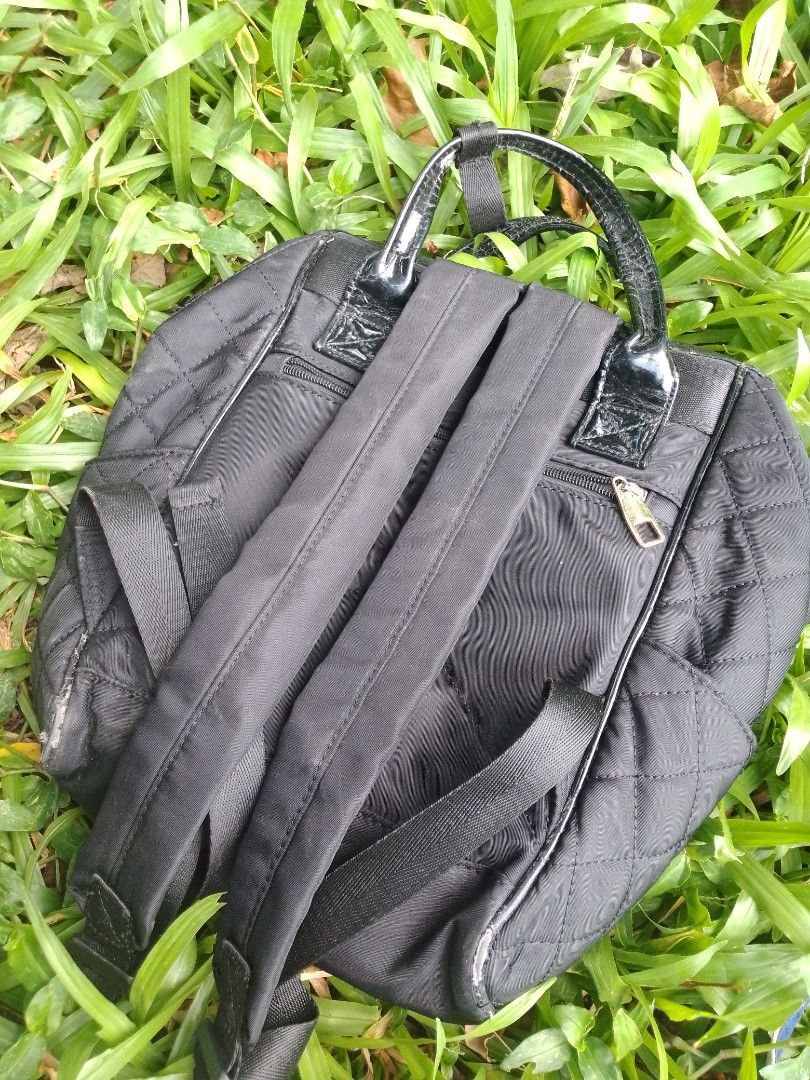 Secosana Black Quilted Backpack with Handles (Category: Backpacks) located in Tabaco. Submitted by cuniie (Listing ID 1464912956, Image 3). Description: - Brand: Secosana - Material: Durable black quilted nylon with shiny patent leather top handles - Features: Front zipped pocket, secure top zip closure, and adjustable back straps - Hardware & Logo: Elegant gold-tone hardware with a triangular Secosana metal logo plate - Condition: Shows some pee