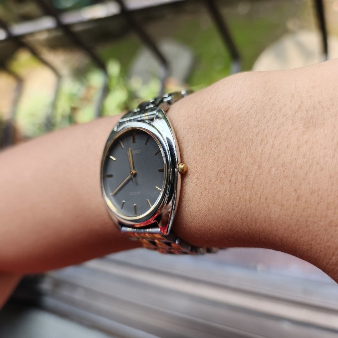 Seiko Lucent (Category: Women's Watches) located in Manila. Submitted by altlazo23 (Listing ID 1464923414, Image 2). Description: - Brand/Model: Seiko Lucent Classic Dress Watch - Dial: Dark grey dial with elegant gold hands and markers - Bracelet: Two-tone silver and gold standard links bracelet with a secure folding clasp - Design: Crown positioned on the right side - Condition: Clean crystal with minimal signs of wear on the case and band - St