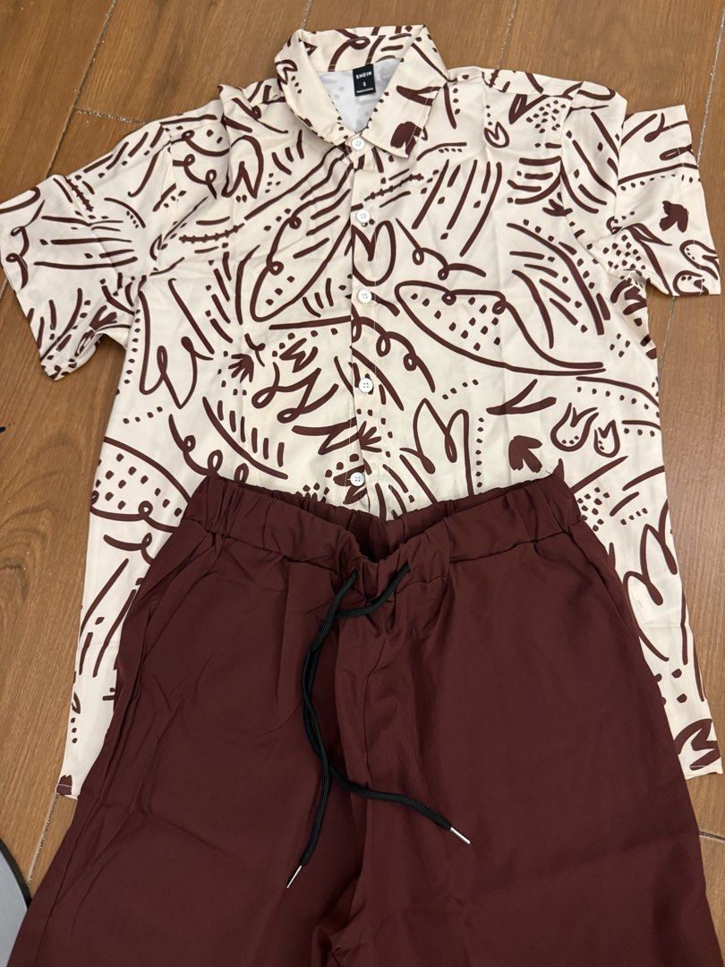 SHEIN Abstract Print Shirt and Solid Shorts Set Size S (Category: Sets & Coordinates) located in Bulacan. Submitted by emjay_17 (Listing ID 1464890672, Image 2). Description: - Brand: Shein - Size: Small (Brand new with tags!) - Top: Short-sleeve button-down shirt with a brown abstract doodle pattern on off-white - Bottoms: Solid dark brown shorts with an elasticated waistband and black drawstring - Material: Lightweight and breathable, ideal for