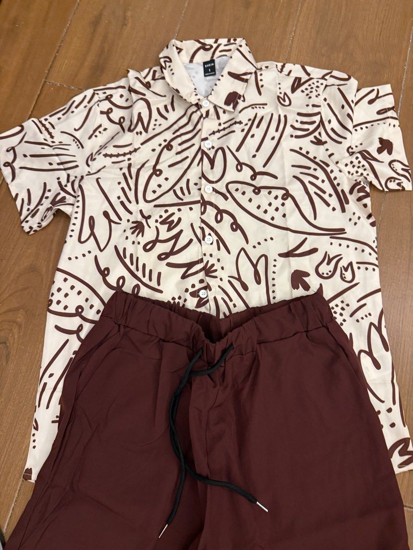 SHEIN Abstract Print Shirt and Solid Shorts Set Size S (Category: Sets & Coordinates) located in Bulacan. Submitted by emjay_17 (Listing ID 1464890672, Image 1). Description: - Brand: Shein - Size: Small (Brand new with tags!) - Top: Short-sleeve button-down shirt with a brown abstract doodle pattern on off-white - Bottoms: Solid dark brown shorts with an elasticated waistband and black drawstring - Material: Lightweight and breathable, ideal for