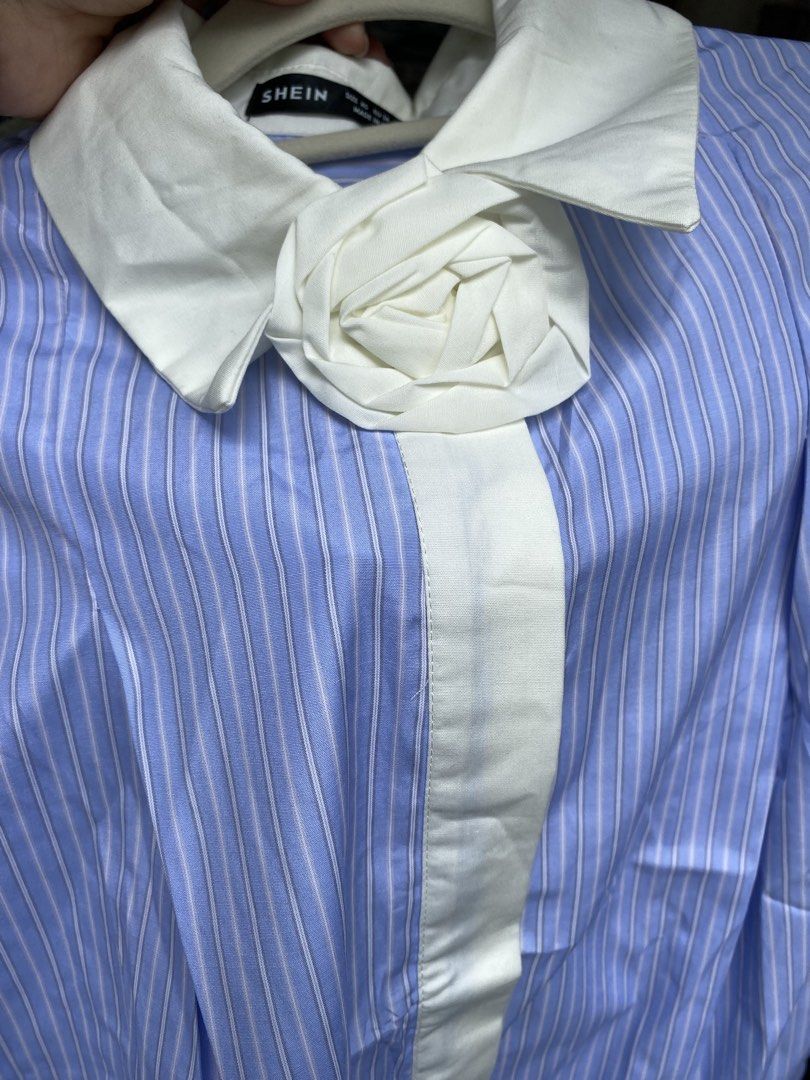 SHEIN Blue and White Striped Collared Shirt (Category: Shirts) located in Pateros City. Submitted by shin_0221 (Listing ID 1464796561, Image 2). Description: - Brand: SHEIN - Design: Blue and white stripes with contrasting white collar, placket, and cuffs - Unique Detail: Built-in fabric rose right on the collar - Fit: Relaxed fit, long sleeves, button-front closure - Xs on tag but fit to M to L - Fabric: Lightweight and comfortable - Style: Smar