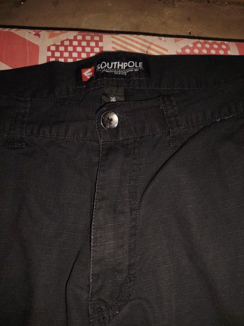 Southpole Black Cargo Shorts Size 36 (Category: Shorts) located in Roxas, Palawan. Submitted by act_thrift_palawan (Listing ID 1464869817, Image 3). Description: - Brand: Southpole - Size: 36 waist - Color: Black - Fabric: Sturdy with ripstop grid texture - Pockets: Multiple utility pockets with button closures - Closure: Button fly front - Details: Branded waistband label inside - Condition/Use: Great casual shorts for daily wear.