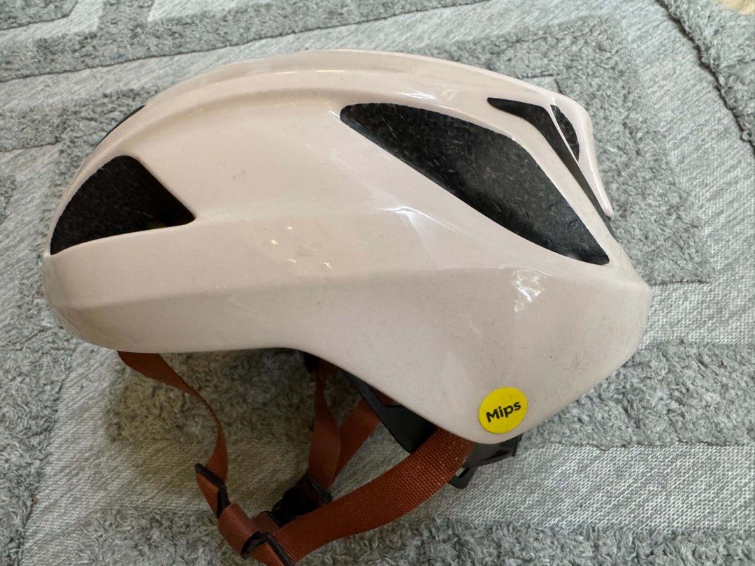 Specialized Bike Helmet with MIPS Beige (Category: Bicycles) located in Bacoor. Submitted by luvtoshoppe (Listing ID 1464813348, Image 3). Description: - Brand: Specialized bicycle helmet - Color: Soft beige with brown straps and black buckle - Safety: Equipped with MIPS safety system for enhanced head protection - Ventilation: Multiple ports on top and sides for optimal airflow - Branding: Orange Specialized logo on front and rear.