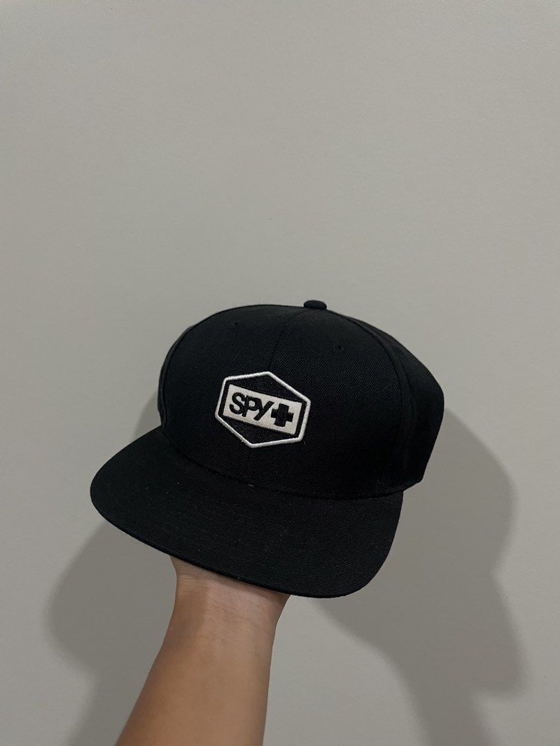 SPY+ Black Flat Brim Snapback Cap (Category: Caps & Hats) located in Bacolod City. Submitted by jmcercado (Listing ID 1464964967, Image 1). Description: - Brand: SPY+ - Color: Classic Black - Style: Snapback with flat brim - Details: Embroidered hexagon logo patch on the front with clean stitching - Condition: Brand new / Great everyday hat that matches any outfit.