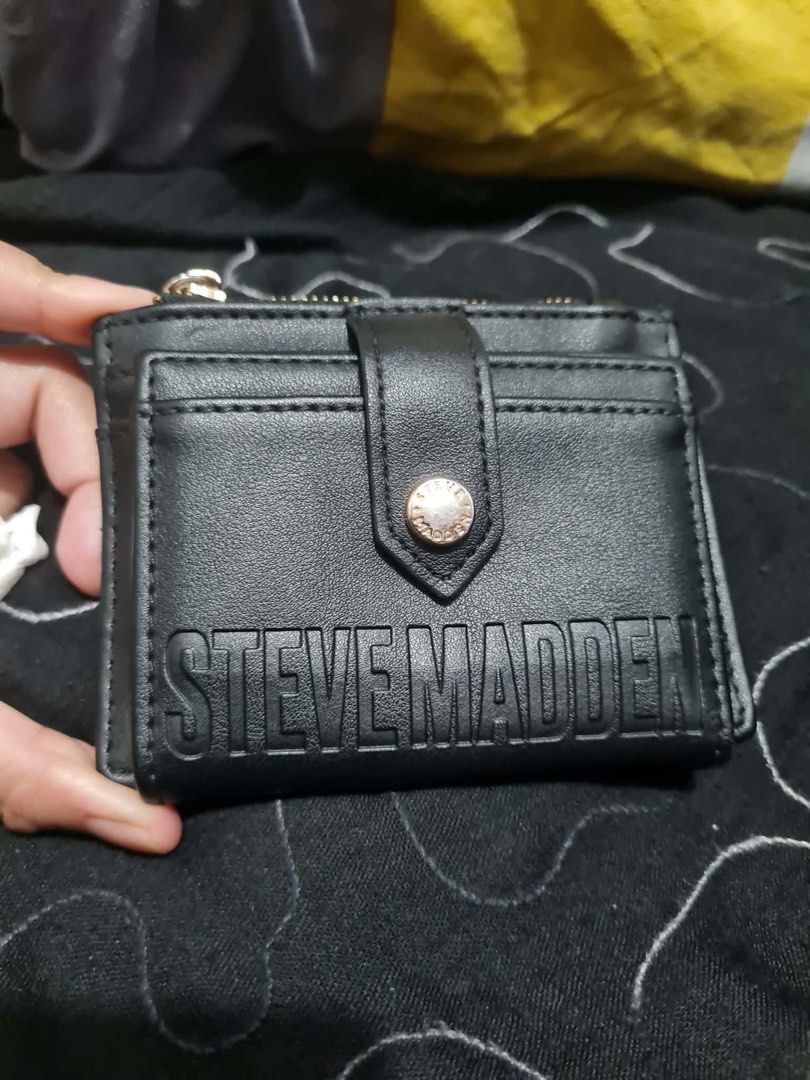 Steve Madden Black Card Holder Wallet (Category: Wallets & Card holders) located in San Juan City. Submitted by janine_0791 (Listing ID 1464904149, Image 1). Description: - Brand: Steve Madden - Color: Classic Black with chic gold-tone hardware - Storage: Multiple card slots, clear ID window, and secure top zipper compartment - Branding: Features an embossed logo on the front and a metallic plaque on the back - Design: Compact size that easily fi