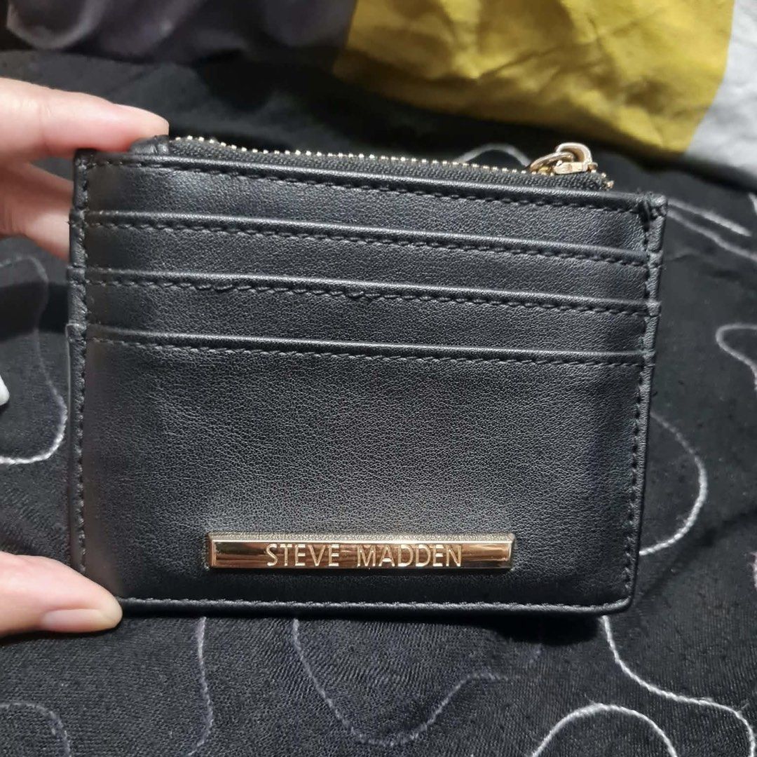 Steve Madden Black Card Holder Wallet (Category: Wallets & Card holders) located in San Juan City. Submitted by janine_0791 (Listing ID 1464904149, Image 3). Description: - Brand: Steve Madden - Color: Classic Black with chic gold-tone hardware - Storage: Multiple card slots, clear ID window, and secure top zipper compartment - Branding: Features an embossed logo on the front and a metallic plaque on the back - Design: Compact size that easily fi