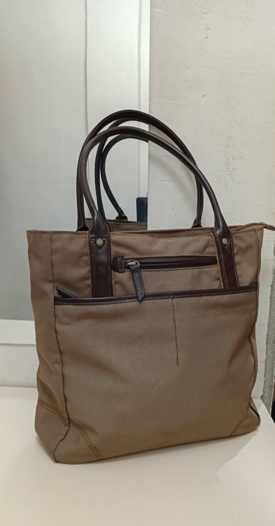 Structured Canvas & Rolled leather handle Everyday Tote Bag (Category: Tote Bags) located in Navotas City. Submitted by ms.soulana (Listing ID 1464795448, Image 2). Description: - Brand: NafNaf - Material: Durable brown canvas with dark brown leather handles and trim - Closure: Secure top zipper closure - Pockets: Front zip pocket and open slip pocket for easy access - Interior: Clean lining with a roomy interior that easily fits daily essentials
