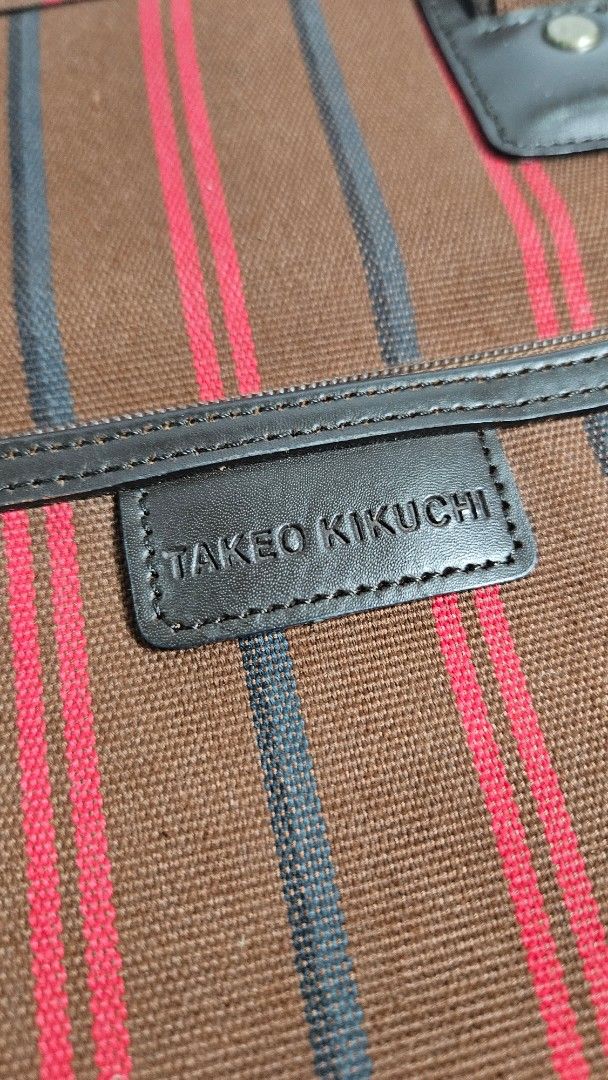 Takeo Kikuchi Brown Striped Tote Bag (Category: Tote Bags) located in Alfonso. Submitted by jbcamet (Listing ID 1464909033, Image 2). Description: - Brand: Takeo Kikuchi - Color: Brown with red and dark stripes - Material: Durable fabric with a structured base - Straps: Sturdy dual shoulder straps for comfortable carrying - Interior: Clean interior lining with stitched brand label - Condition: Excellent, well-maintained - Use: Versatile everyday 